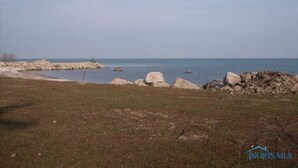 A coastal landscape with a rocky shoreline, a grassy area, and a calm sea. - 1ST floor Condo NO STAIRS, beaches ,pool cedar point camp perry marsh parks,<br> (Oak Harbor)