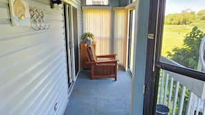 A covered porch with a wooden bench, a potted plant, and a view of a green landscape. - 1ST floor Condo NO STAIRS, beaches ,pool cedar point camp perry marsh parks,<br> (Oak Harbor)