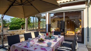 An outdoor dining area with a table set for four, covered by a large umbrella, and surrounded by chairs.