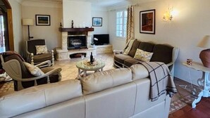 A living room with a sofa, armchairs, a fireplace, and a television.