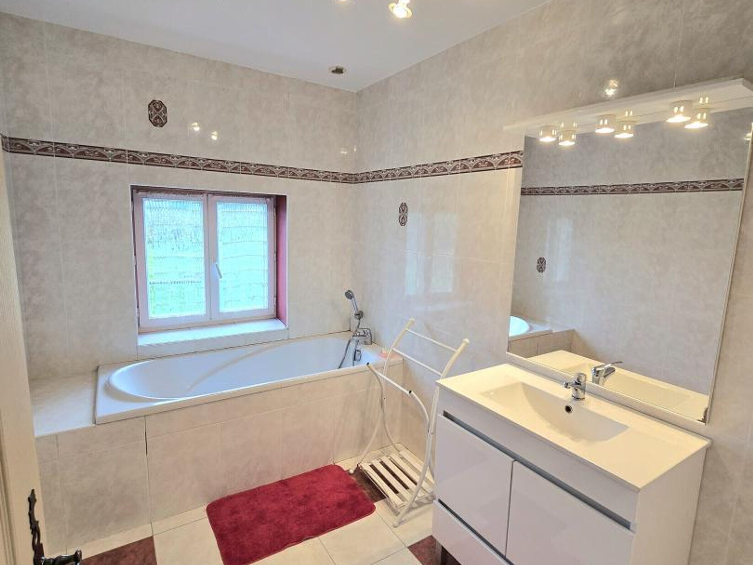A bathroom with a bathtub, a sink, and a window.