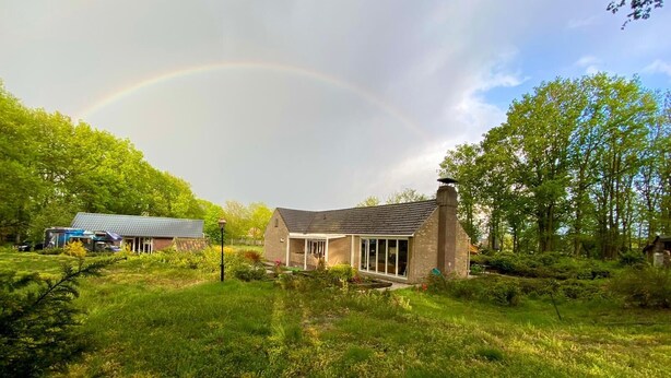 A house with a stone chimney, a glass door, and a garden with grass and trees. - Beautiful 2.5 ha Estate With Forest, Sauna, hot tub (Well)