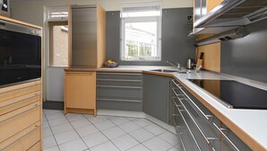 A modern kitchen with a built-in oven, stainless steel appliances, and a window providing natural light. - Beautiful 2.5 ha Estate With Forest, Sauna, hot tub (Well)