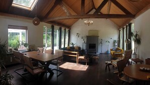 A spacious living area with a high ceiling, large windows, and a fireplace. - Beautiful 2.5 ha Estate With Forest, Sauna, hot tub (Well)