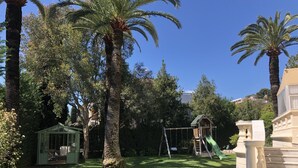 Un jardí exuberant amb palmeres, un tobogan i un porxo.