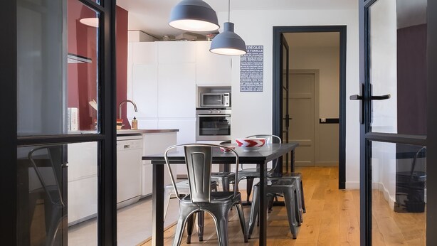 Eine moderne Küche mit Essbereich, Holzboden und Pendelleuchten.
