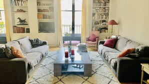 Ein Wohnzimmer mit zwei Sofas, einem Couchtisch und Bücherregalen voller Bücher und DVDs.