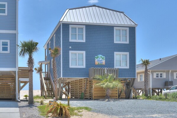 Een gebouw met twee verdiepingen, een blauwe gevel, houten terras en een bordje met de tekst 'On Island Time'.