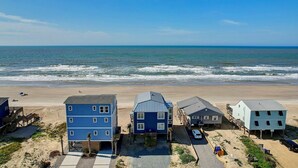 Une propriété située en bord de mer, comprenant plusieurs bâtiments, une plage de sable et l’océan en toile de fond.