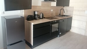 Una cucina compatta con frigorifero, macchina del caffè, tostapane e lavastoviglie.