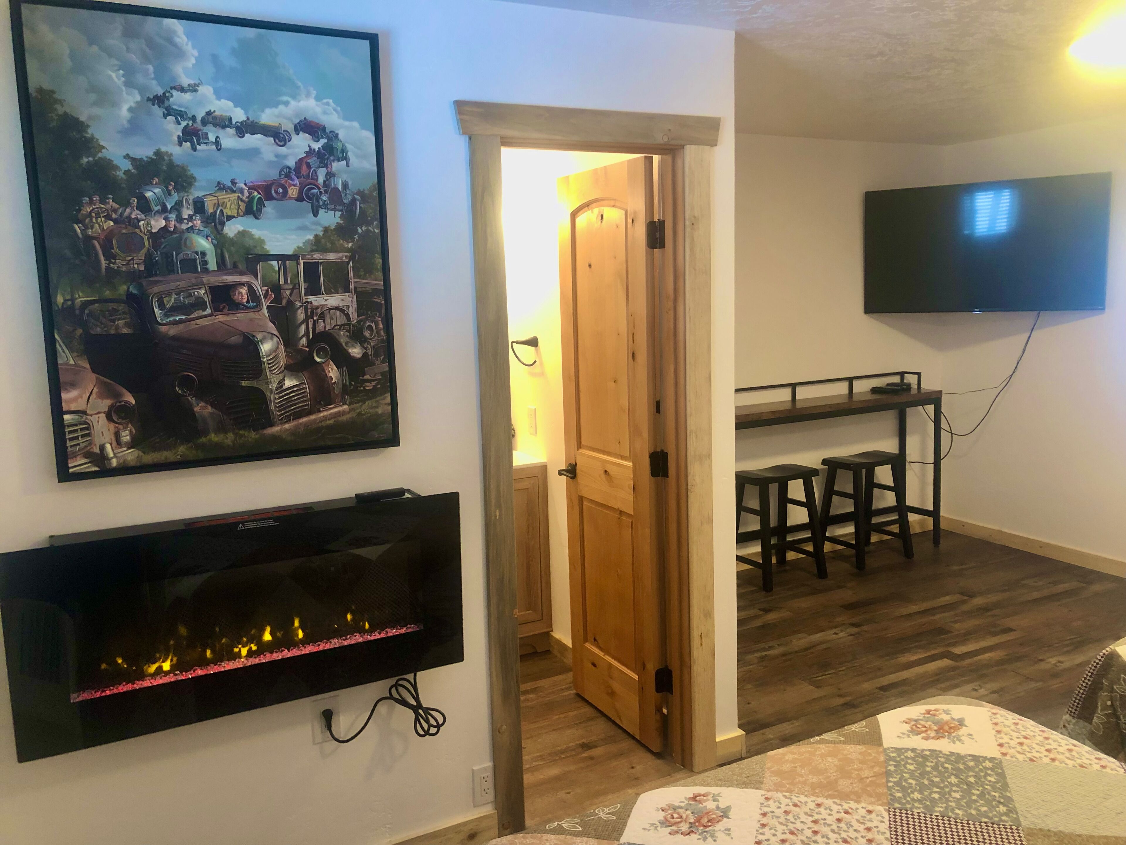 A living room with a fireplace, a television mounted on the wall, and a door leading to another room.