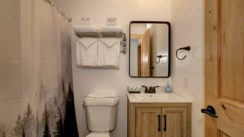 A bathroom with a toilet, a sink, a mirror, and a shower curtain.