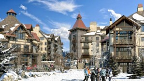 Een besneeuwde skigebied met traditionele chalets, skipistes en skiërs.