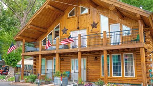 Een houten gebouw in chaletstijl met een balkon, Amerikaanse vlaggen en bloempotten.