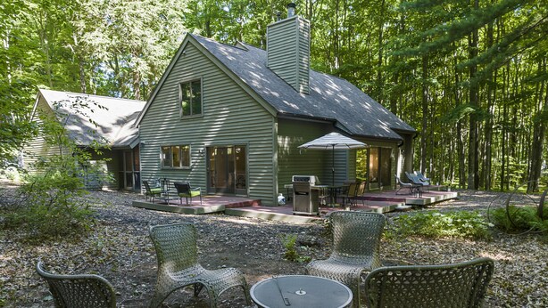 Een groene woning met een terras, buitenmeubilair en een vuurkorf.