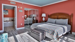 A bedroom with a bed, a bench, a mirror, and a door leading to a bathroom. - 3BR 3.5BA @ EMERALD BEACH! SLEEPS 10! (Panama City Beach)