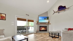 A spacious living room with a fireplace, a television, and a balcony with outdoor seating.