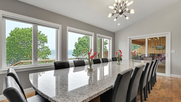 A spacious dining area with a long table, black chairs, and a modern chandelier.