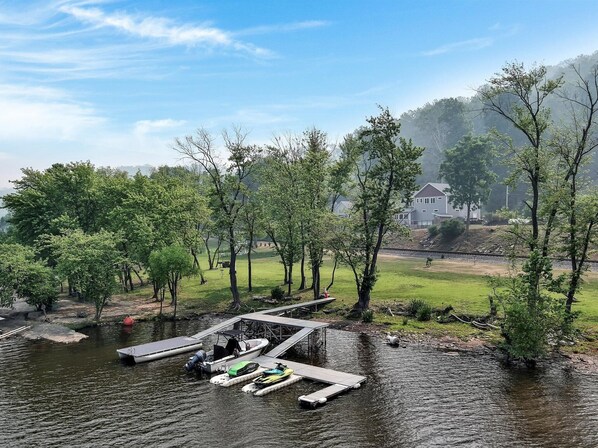 Un embarcadero a orillas del río con barcos y una zona verde con árboles.