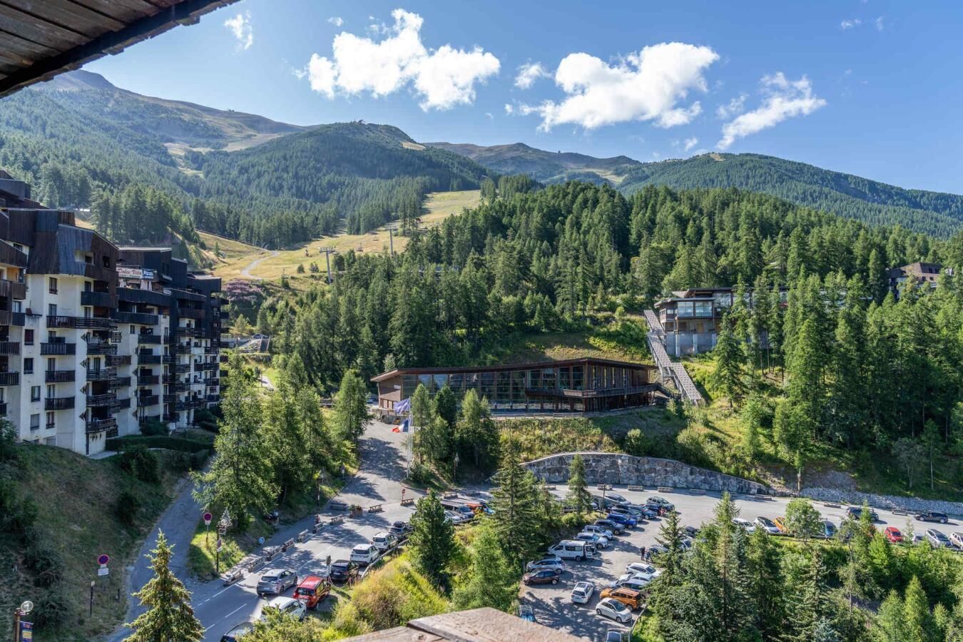 Ein Bergurlaubsort mit Parkplatz, Skilift und Gebäuden, umgeben von Wald.