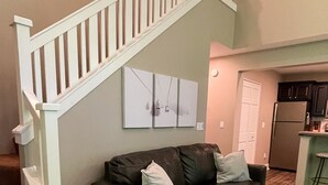 A living room with a dark brown leather sofa, a patterned rug, a wooden coffee table, and a white staircase. - Ski in on Boyneland Run, Slps 18, Fully remodeled (Boyne Falls)
