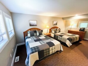 A bedroom with two beds, a dresser, and a nightstand with lamps.