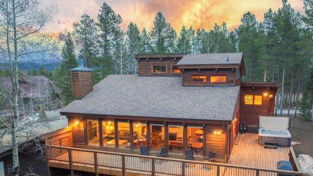 Eine Holzhütte mit einer Terrasse, einem Whirlpool und einem Kamin.