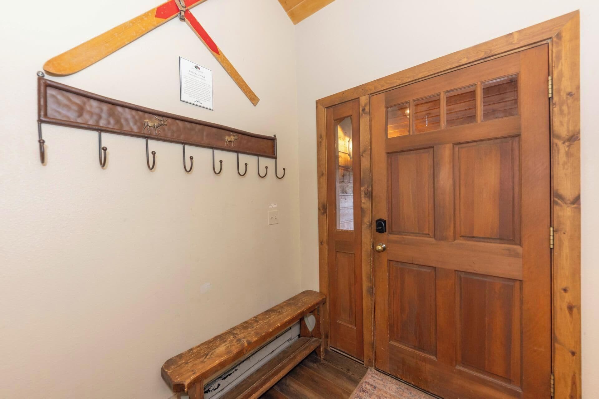 A wooden door with a glass panel, a coat rack with hooks, and a bench.