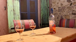 A table set with two wine glasses and a bottle of wine, a striped cushion, and a bench in a rustic outdoor setting. - Maison "moli ère" (Ferrals-les-Corbières)