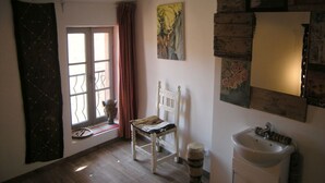 A room with a window, a chair, a sink, and a painting on the wall. - Maison "molière" (Ferrals-les-Corbières)