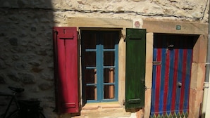 A stone building with a window and a door, a bicycle parked outside, and a sign with the number 20. - Maison "molière" (Ferrals-les-Corbières)