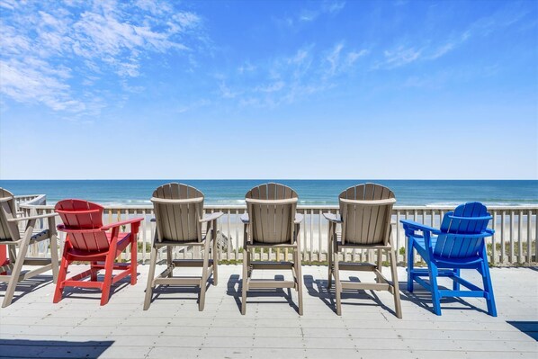 Relax in Adirondack chairs on a deck overlooking the ocean.