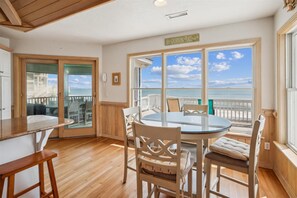 Enjoy ocean views from the balcony through the large glass door. The room features a round table and four comfortable chairs.