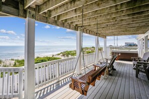 Enjoy the ocean view from this elevated deck with comfortable seating and a clear view of the beach.
