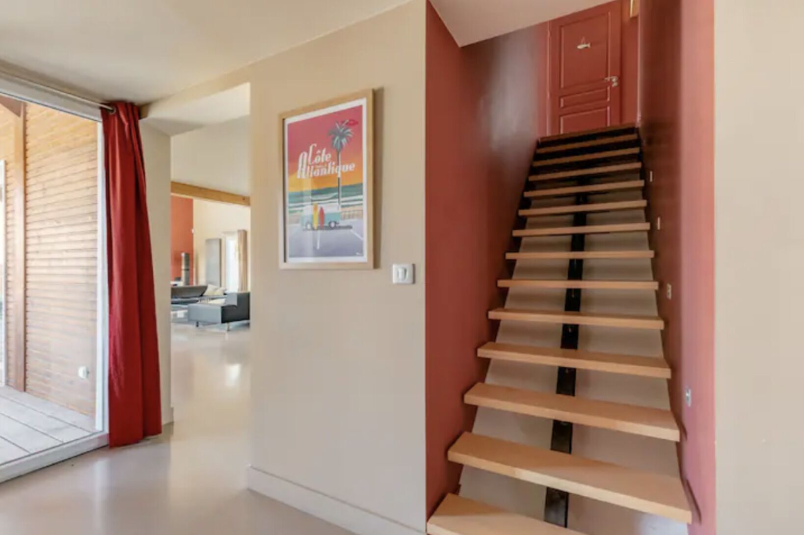 A modern interior with a staircase, a framed picture on the wall, and a glimpse of a living area.
