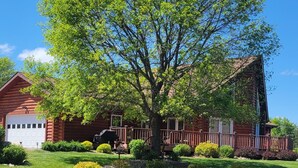 A log cabin with a gravel driveway, surrounded by well-maintained lawns and a large tree. - Log Cabin located minutes from Missouri River, airport, I-90 and downtown. (Chamberlain)