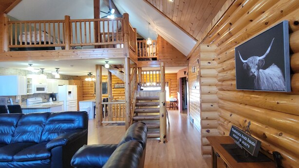 A log cabin interior with a dining area, kitchen, and a living room with leather sofas. - Log Cabin located minutes from Missouri River, airport, I-90 and downtown. (Chamberlain)