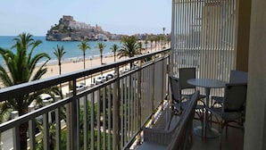 Varanda com móveis de vime com vista para a praia e um edifício histórico.