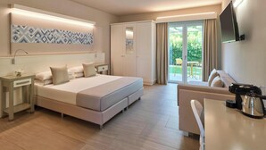 Une chambre d’hôtel moderne équipée d’un grand lit, d’un canapé, d’un bureau avec une bouilloire et d’une télévision.