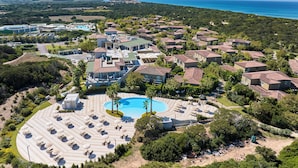 Vue aérienne d’une station balnéaire avec des villas, une piscine et une plage.
