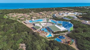 Vue aérienne d’un complexe hôtelier doté de plusieurs piscines, d’un grand bâtiment central et offrant une vue sur l’océan.