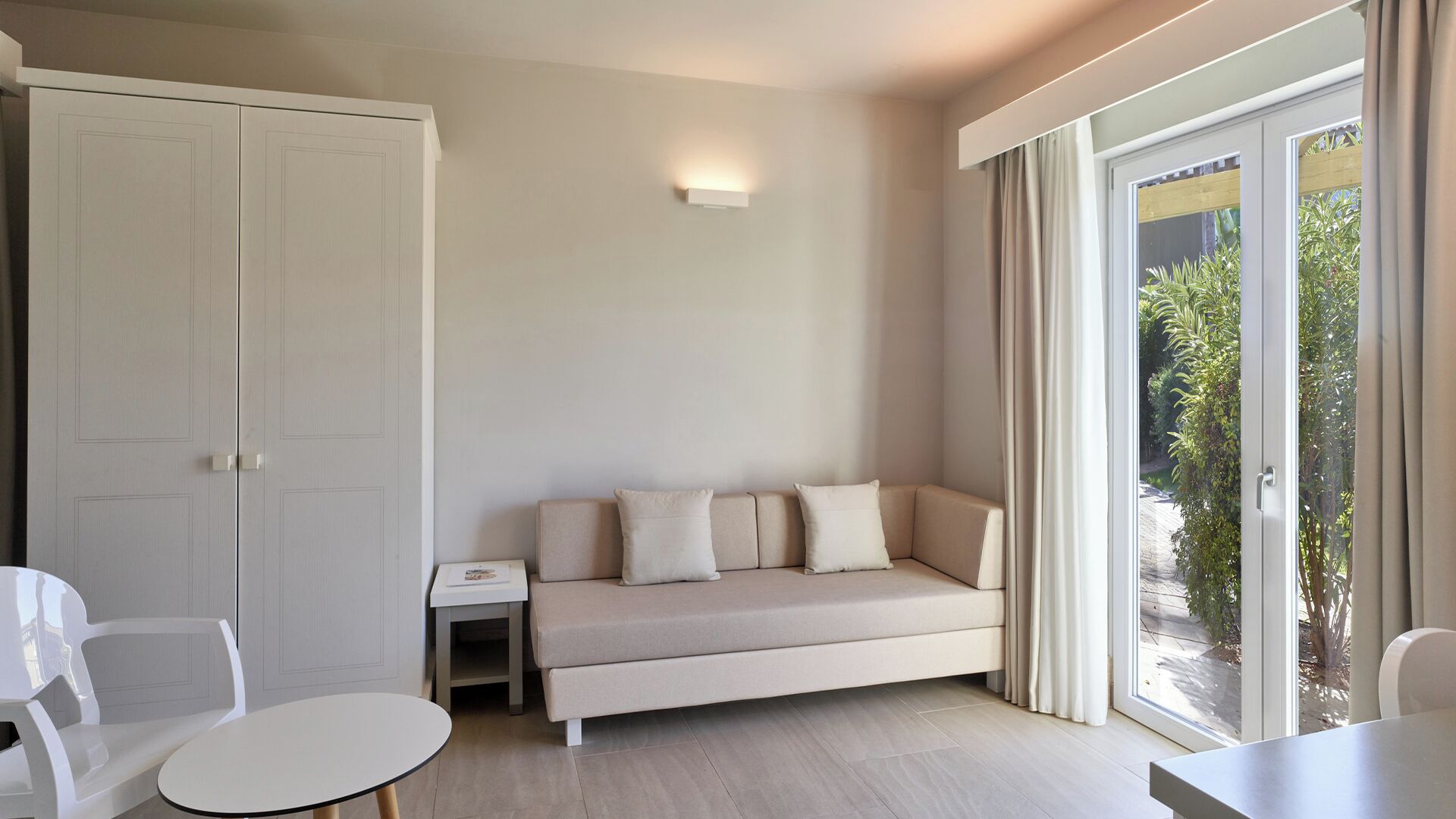 A modern room with a beige sofa, a small table, and a wardrobe.
