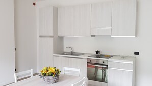 A modern kitchen with white cabinets, a stainless steel sink, and a built-in oven. - Vista Lago Spettacolare (Abbadia Lariana)