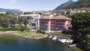 A waterfront hotel with a central courtyard, a children's play area, and boats docked at the marina. - Vista Lago Spettacolare (Abbadia Lariana)