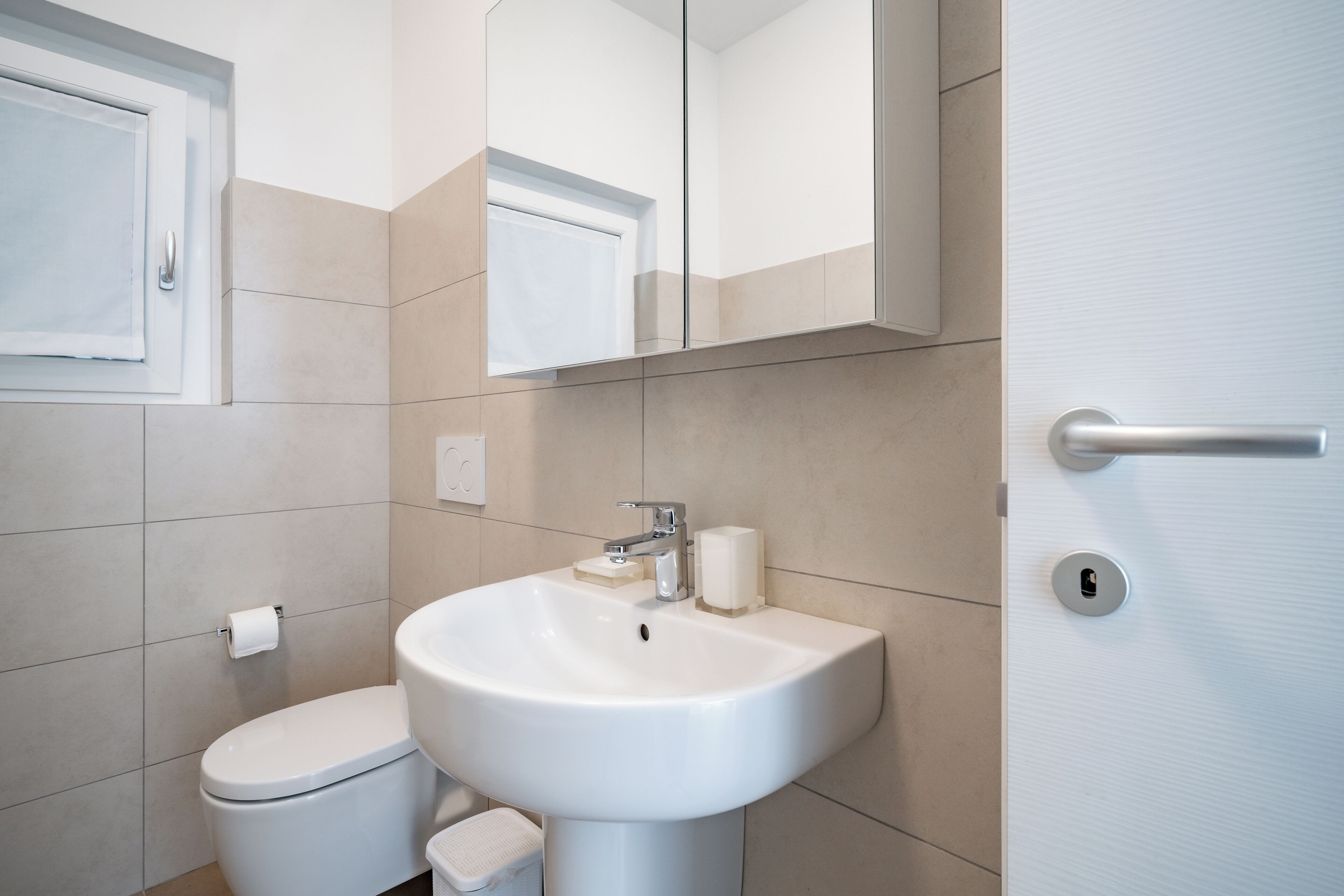 Un baño moderno con inodoro, lavamanos y espejo.
