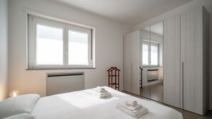 A modern bedroom with a large bed, a wardrobe, and a mirror. - Vista Lago Spettacolare (Abbadia Lariana)