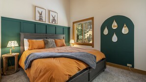 Quarto com cama, duas mesas de cabeceira, janela e detalhes decorativos nas paredes.