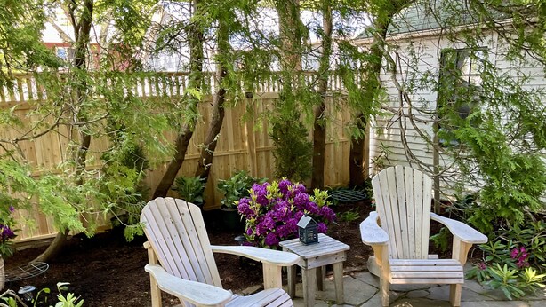 Due poltrone Adirondack con un tavolino e una lanterna in un giardino.