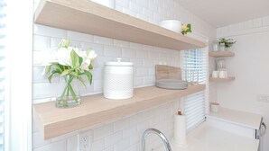 A kitchen with white subway tiles, wooden shelves, and a white vase with flowers. - Arden House DT Mystic 3BR Lux Family Getaway (Mystic)