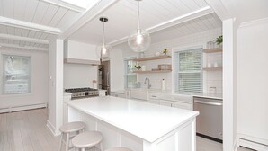 A modern kitchen with a central island, pendant lighting, and white cabinetry. - Arden House DT Mystic 3BR Lux Family Getaway (Mystic)